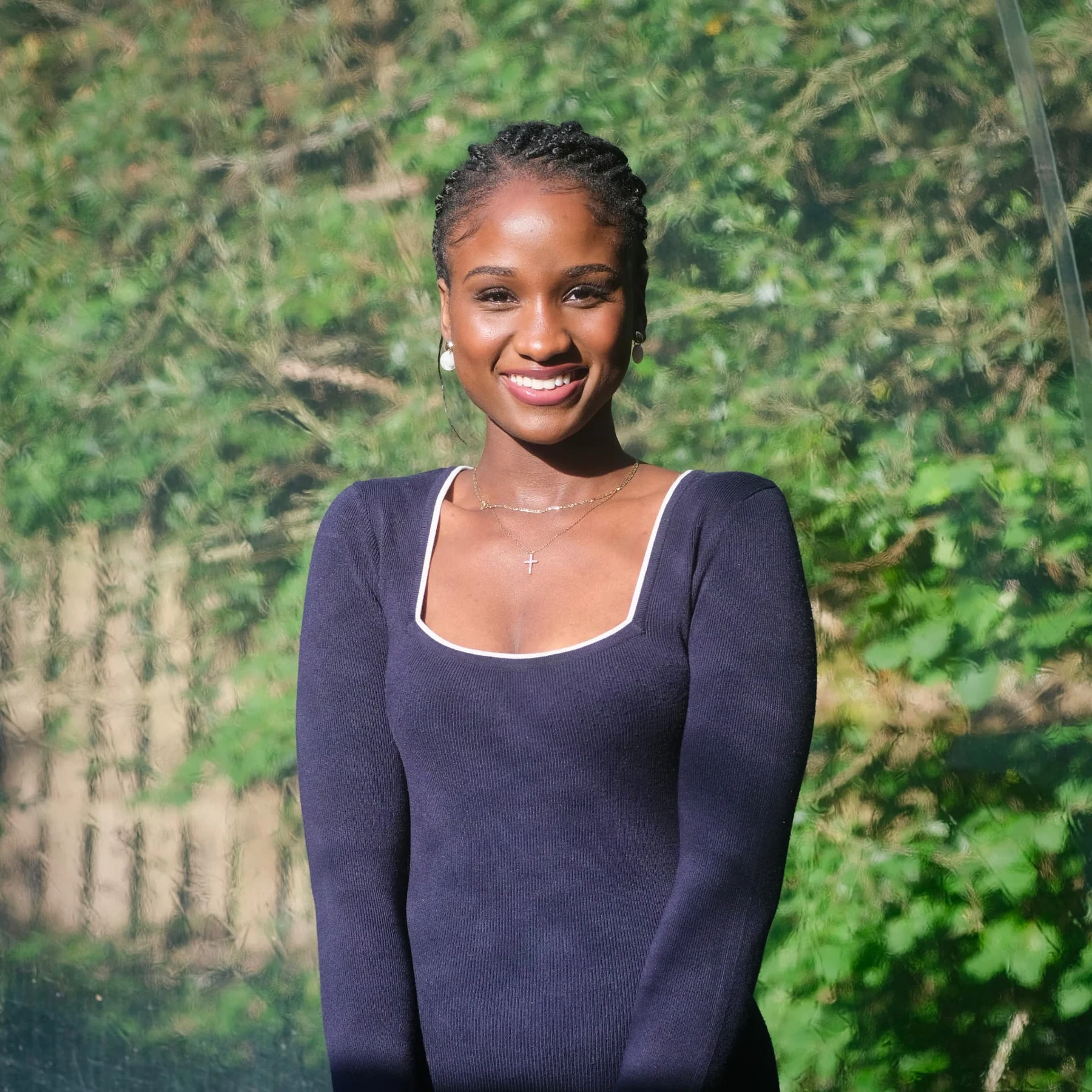 Elizabeth Zion smiling outdoors against greenery in a navy outfit